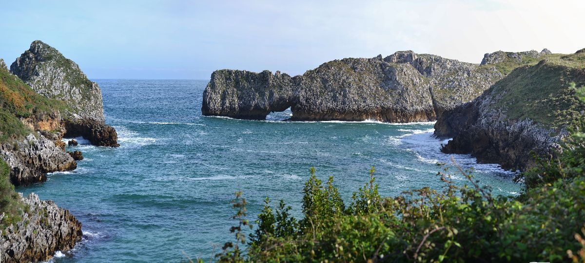 Vista del mar Cantábrico, en día soleado, donde se ve un arco de piedra que se ha formado de manera naural